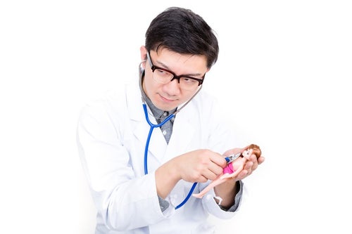 人形に聴診器を当ててお医者さんごっこをする男性の写真