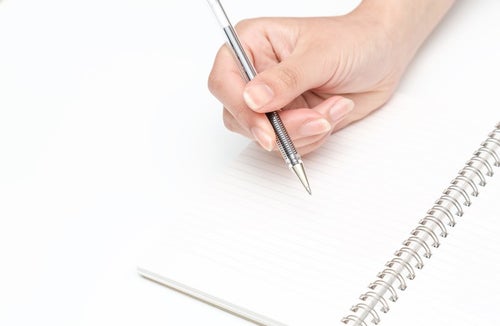 ペンを握る手とノートの写真