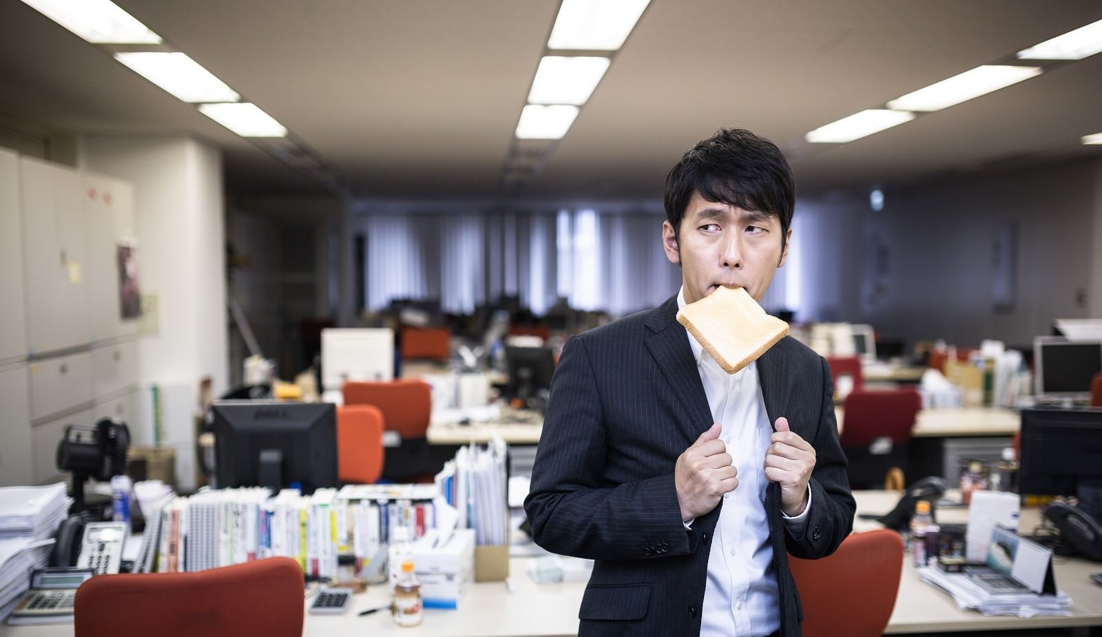 「残業中トーストを食べ気合を入れる新卒社員」の写真［モデル：大川竜弥］