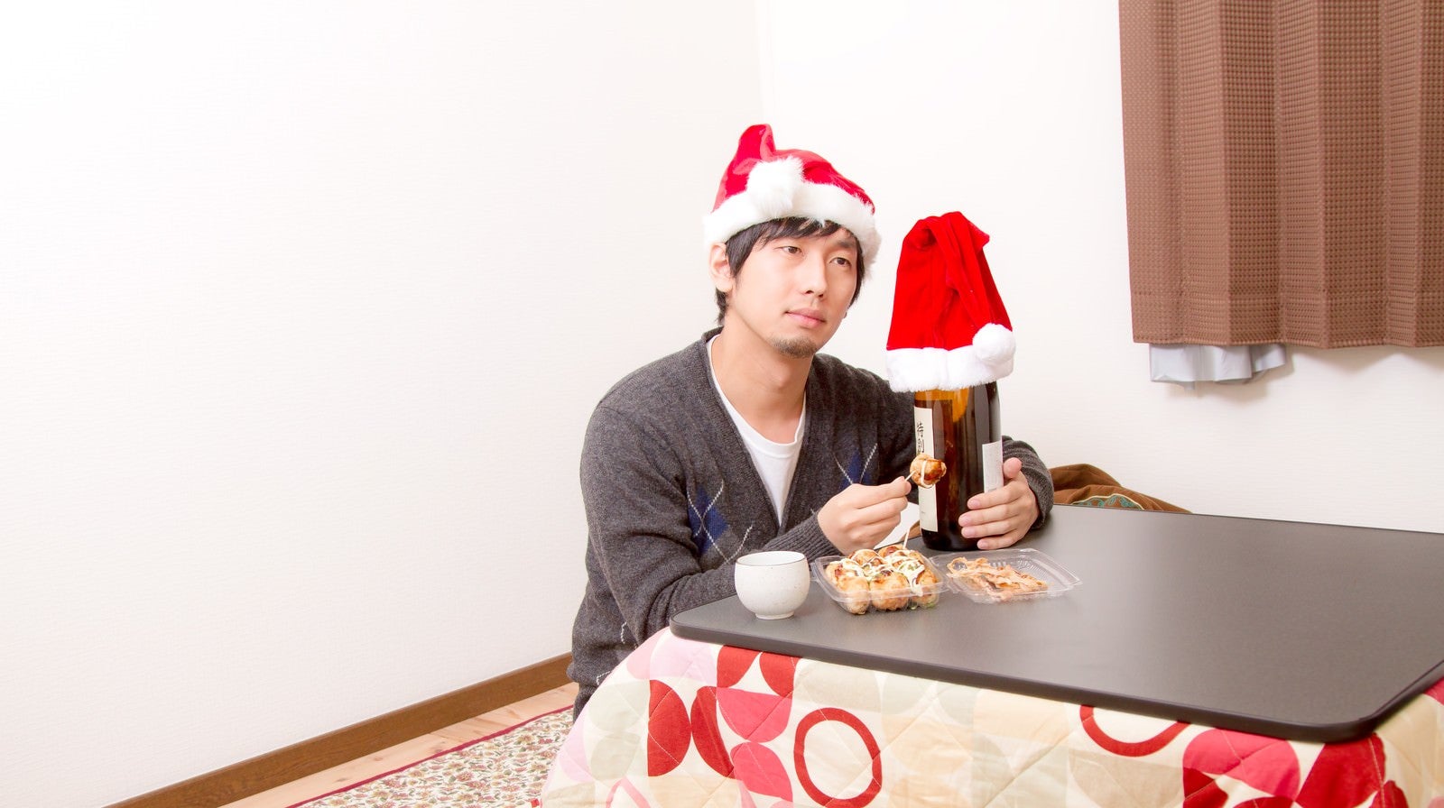 「コタツで寂しくクリスマスを過ごす男性」の写真［モデル：大川竜弥］