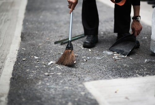 渋谷の街をチリトリとホウキで清掃する人の写真