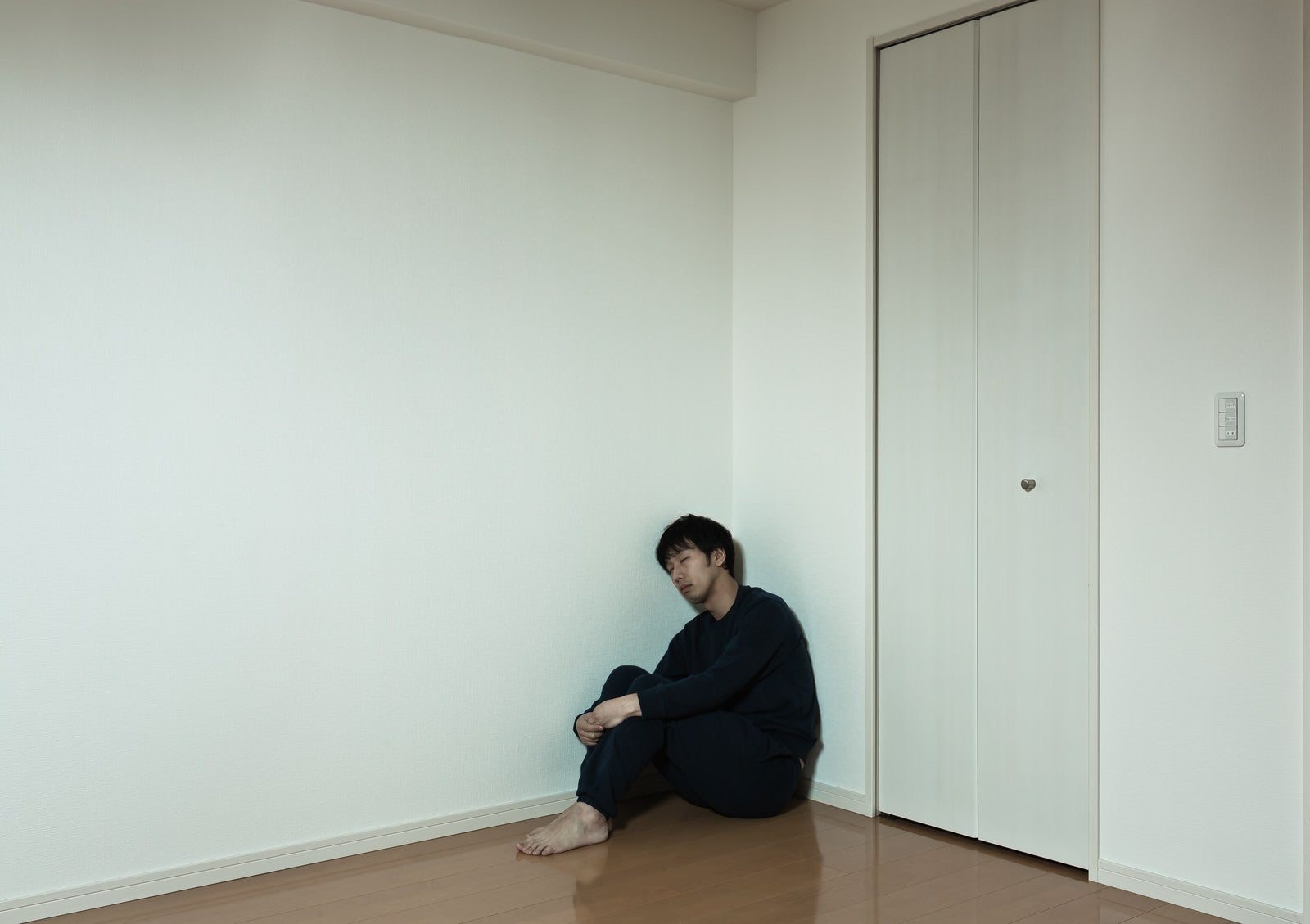 「部屋の隅っこで独り寂しく寝落ちする男性」の写真［モデル：大川竜弥］