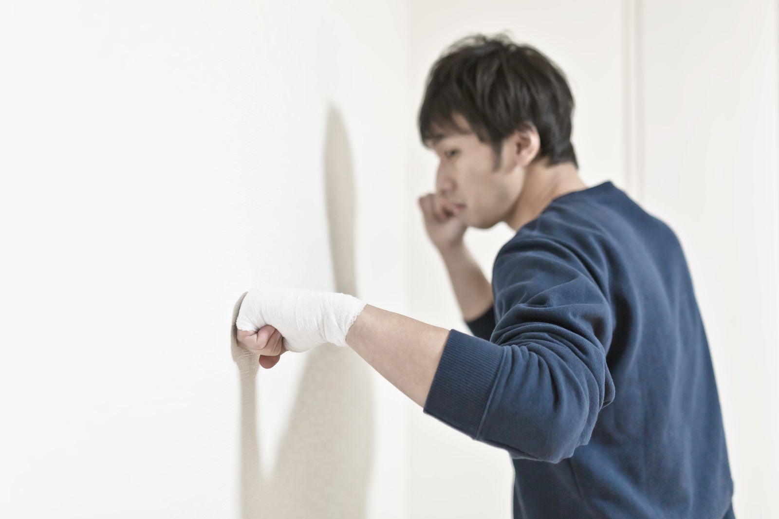 「包帯をしてまで壁を殴り続ける男性」の写真［モデル：大川竜弥］