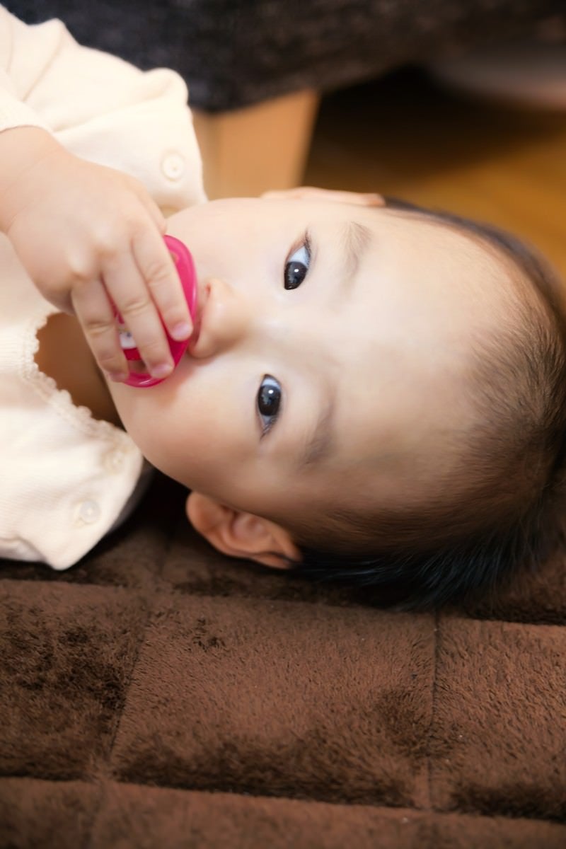 「おしゃぶりを手で触る赤ちゃん」の写真［モデル：あんじゅ］