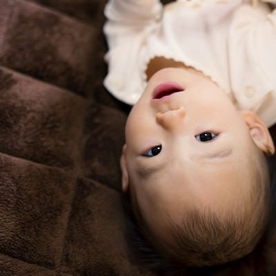 床に寝転び微笑む赤ちゃんの写真