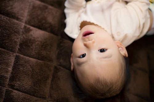 床に寝転び微笑む赤ちゃんの写真