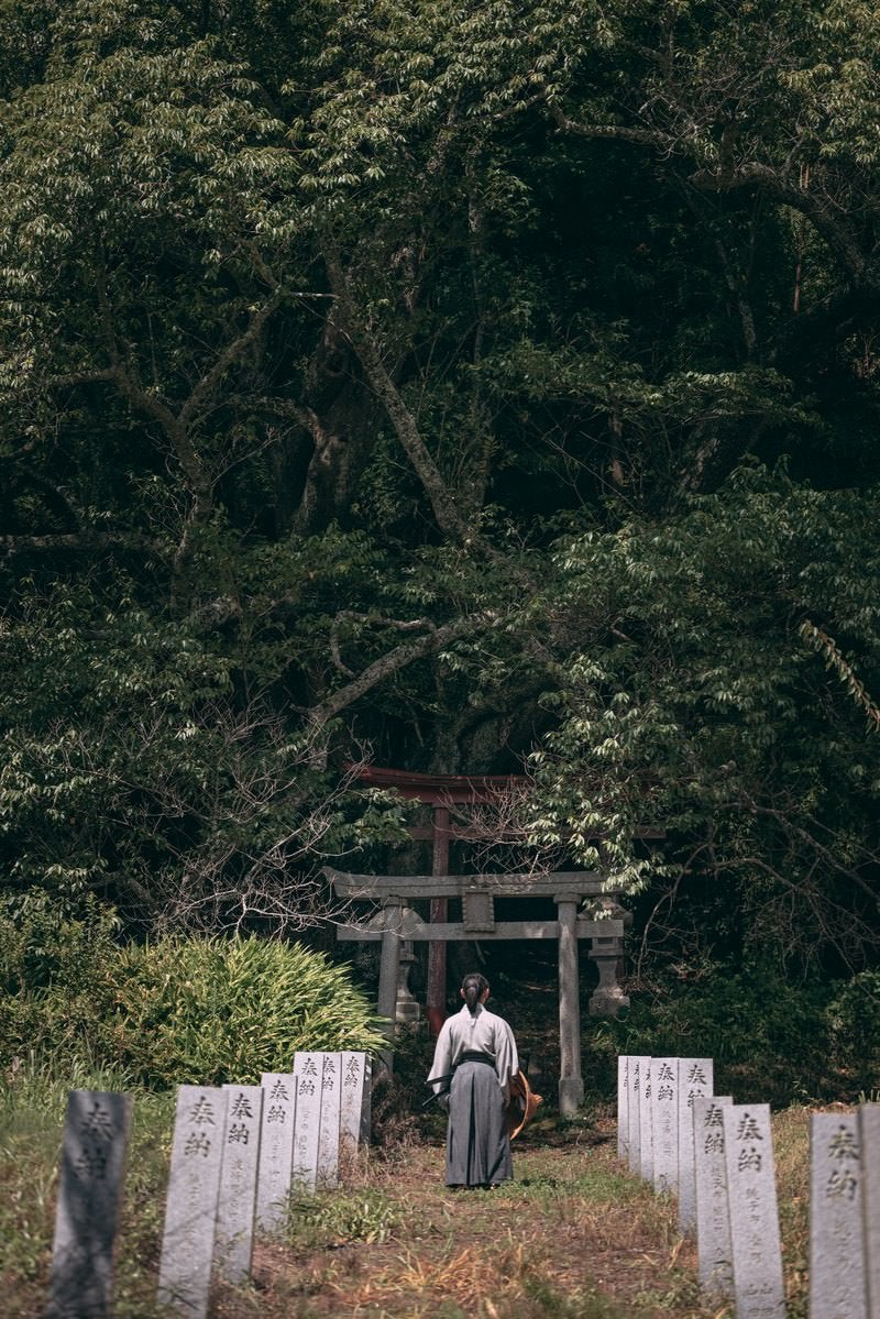 「鳥居へと続く奉納石柱と武士の後ろ姿」の写真［モデル：まーこ］