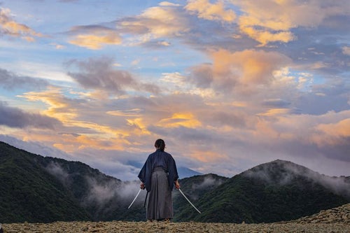 夕日に染まった空と二刀流の侍の写真