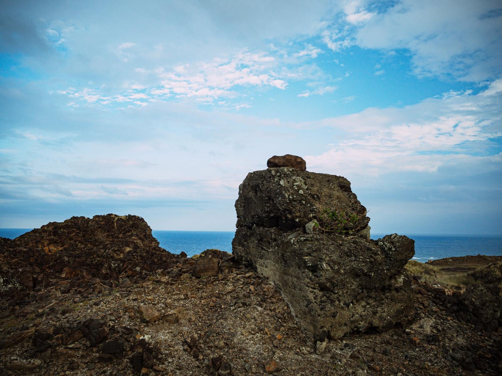 Toachika (pillbox) ruins remaining on lava-formed rocky shores on the coast of Iwo Jima (Iōjima) with horizon stretching across blue sky