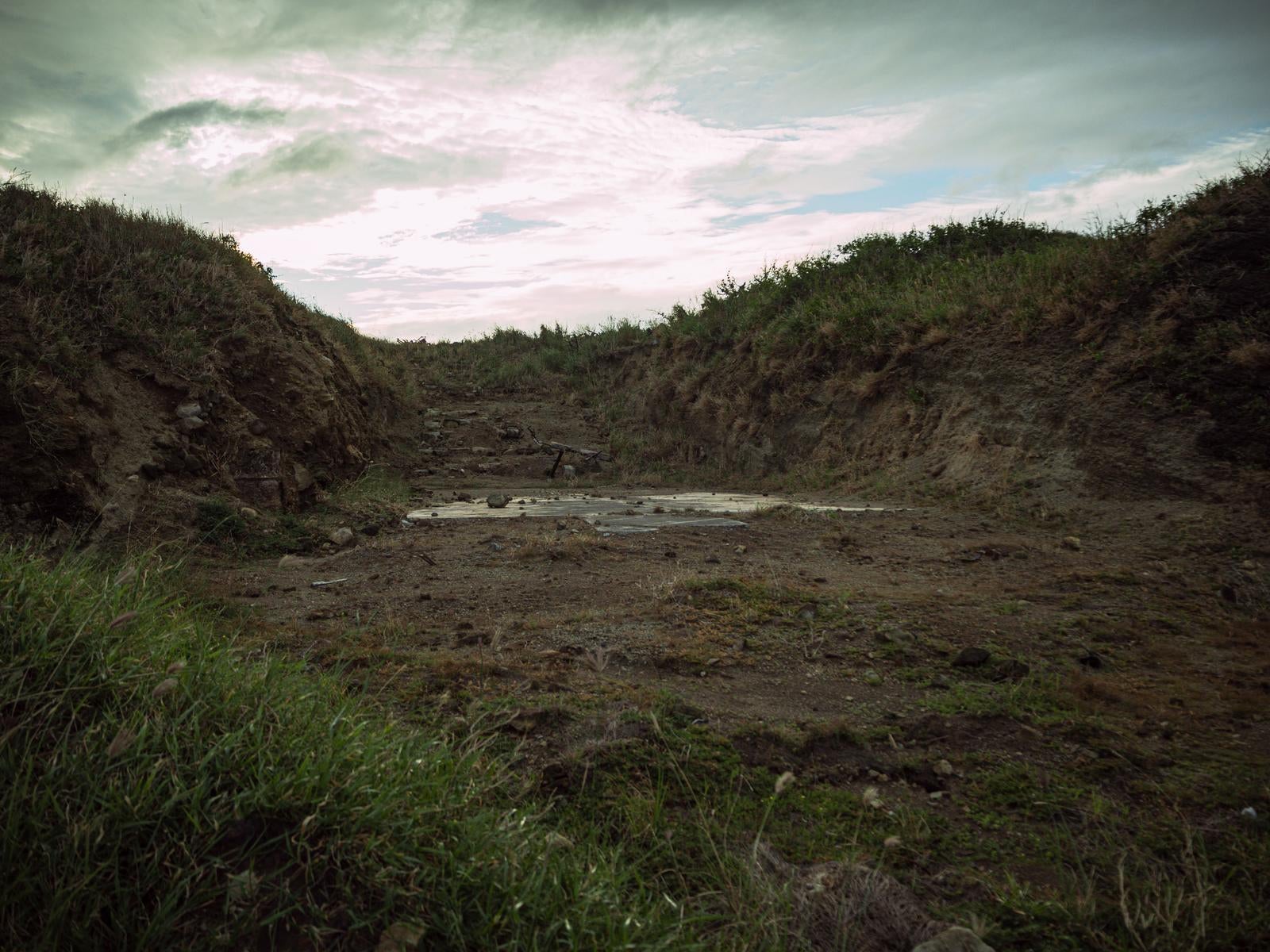 「塹壕に残るコンクリートの遺構と曇り空の静寂」の写真