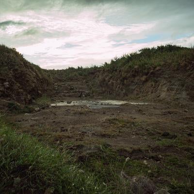 塹壕に残るコンクリートの遺構と曇り空の静寂の写真