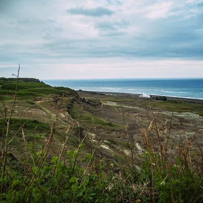 遠景の北硫黄島と荒涼たる大地と青い海の写真