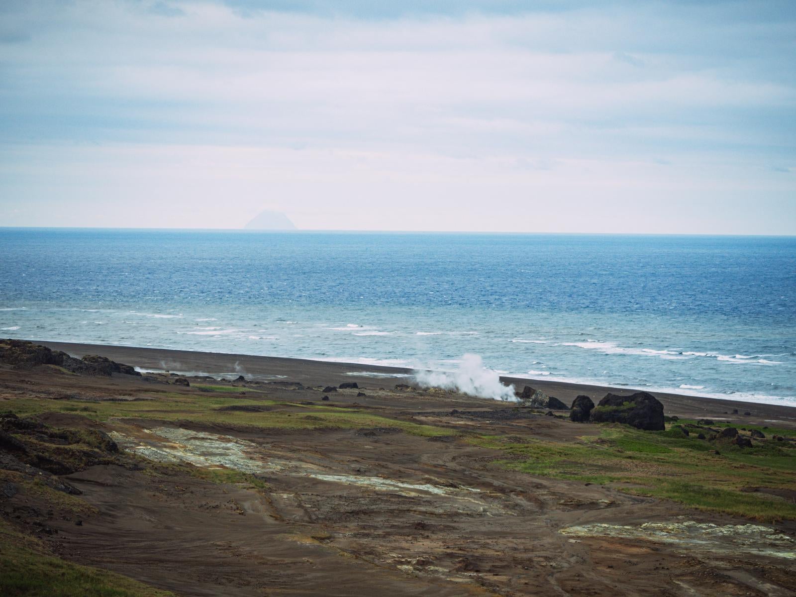 「蒸気立つ海岸線と遠き北硫黄島の島影」の写真
