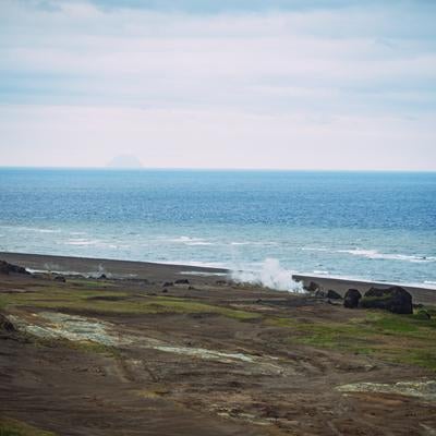 蒸気立つ海岸線と遠き北硫黄島の島影の写真