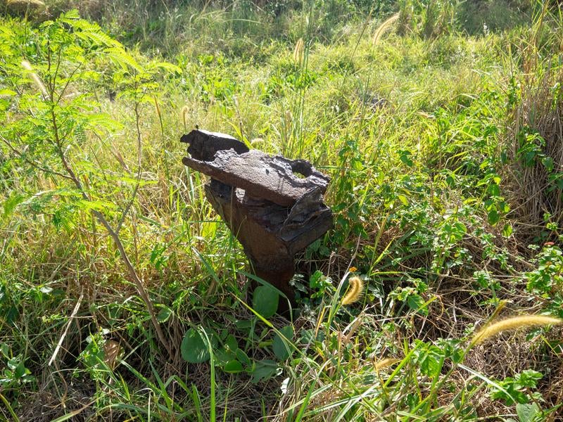 草むらに埋もれた戦争遺跡の銃座の写真
