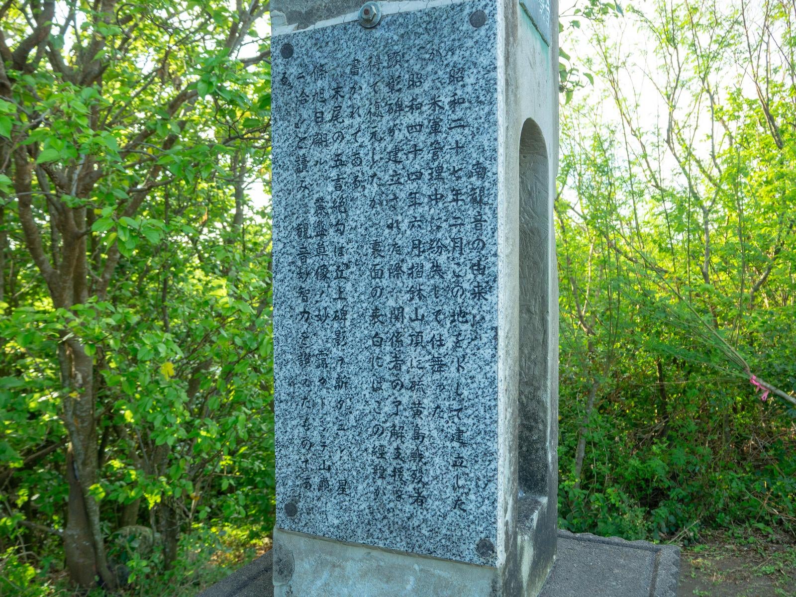 「新緑の森林に静かに佇む戦跡慰霊碑」の写真