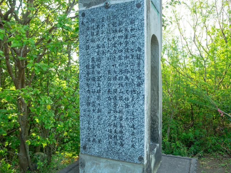 新緑の森林に静かに佇む戦跡慰霊碑の写真