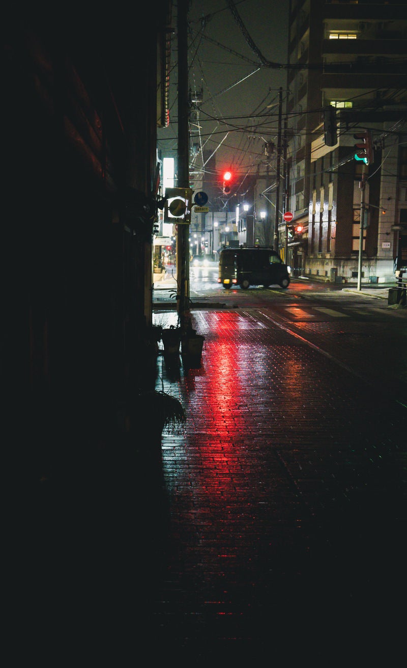 「雨天の赤信号と左折する軽自動車」の写真