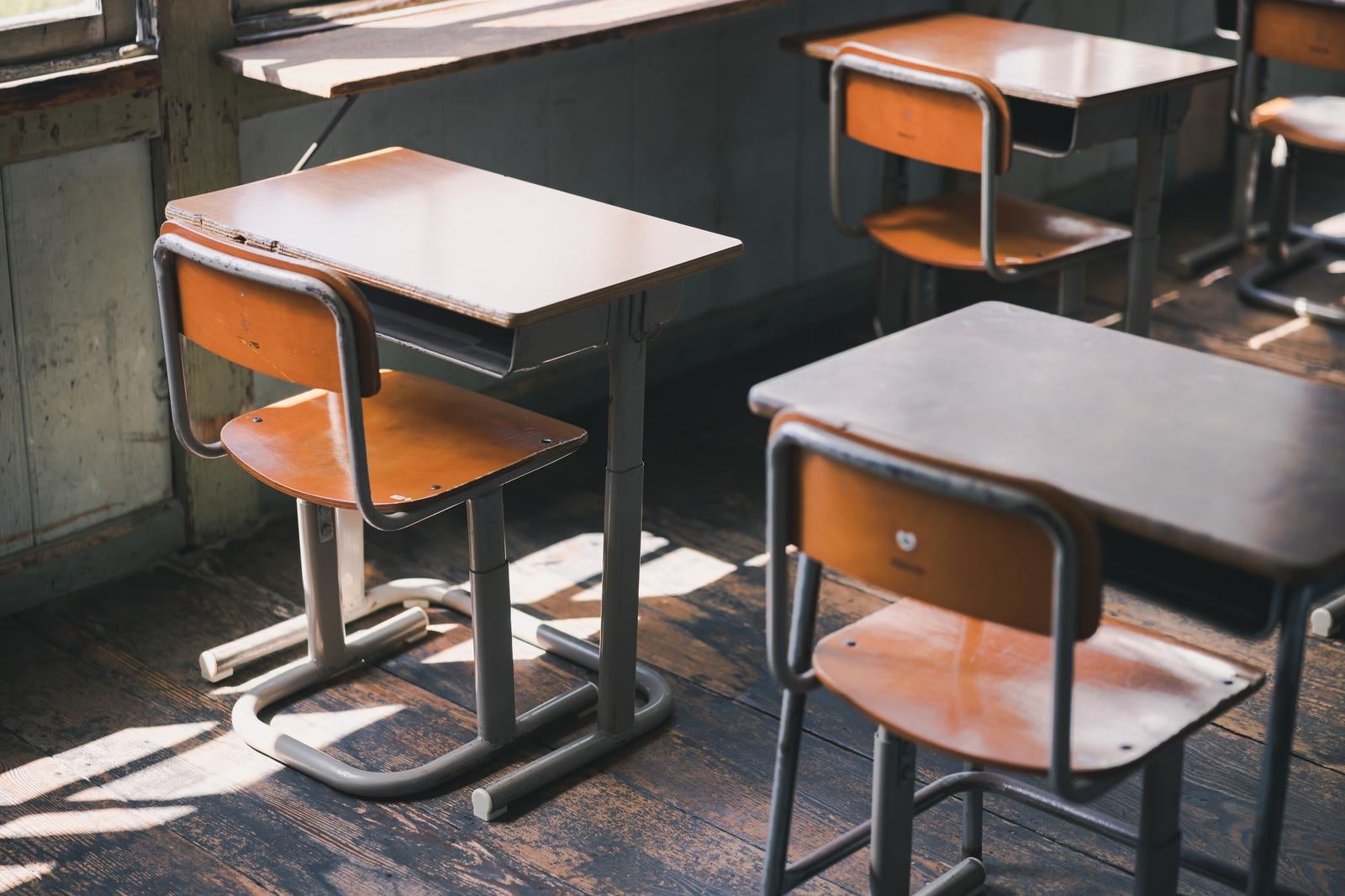 「放課後の学習机と椅子が並ぶ教室」の写真