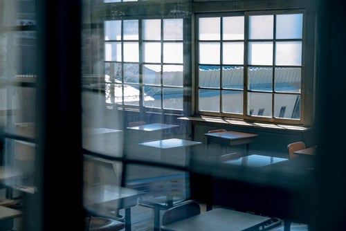 窓ガラス越しの放課後の教室風景の写真