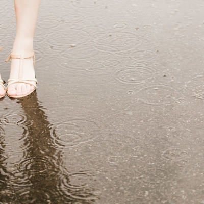 雨で足元がびしょ濡れの女性の写真