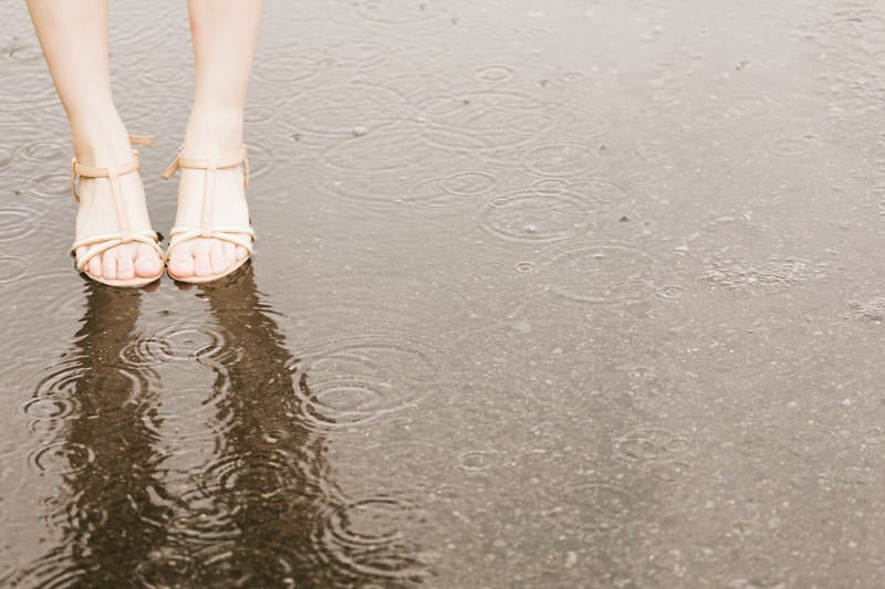 雨で足元がびしょ濡れの女性の写真