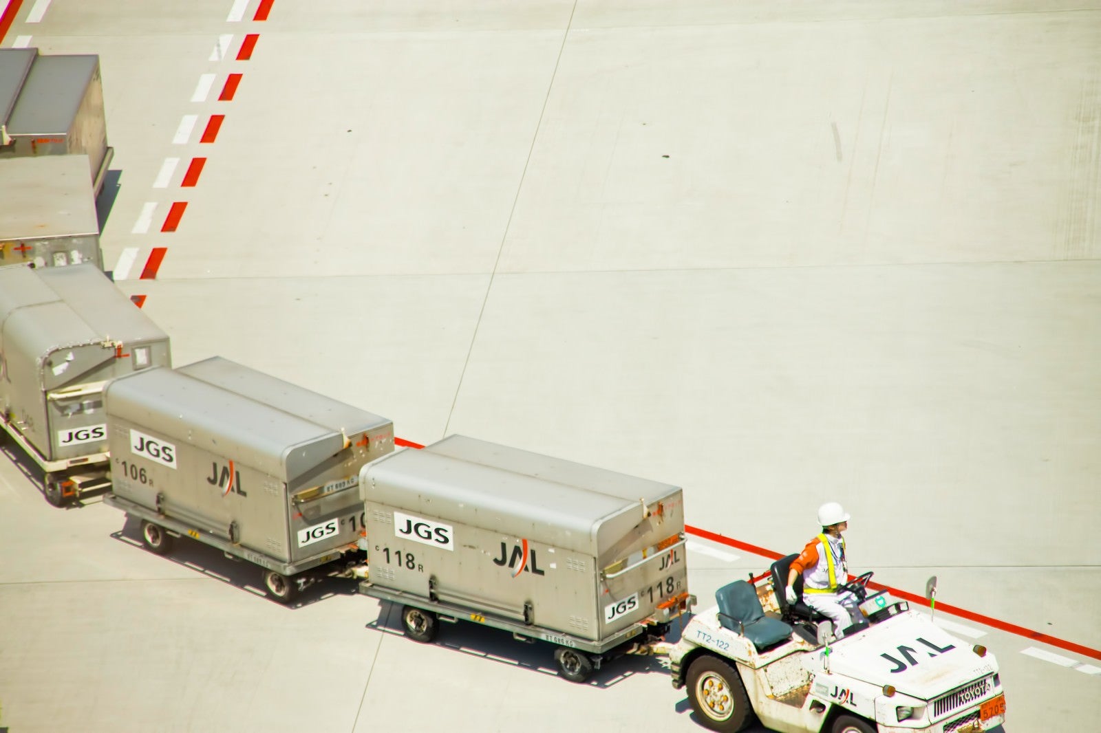 「空港のコンテナを運ぶ車」の写真