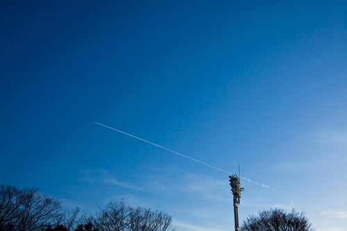青空に伸びる飛行機雲の写真