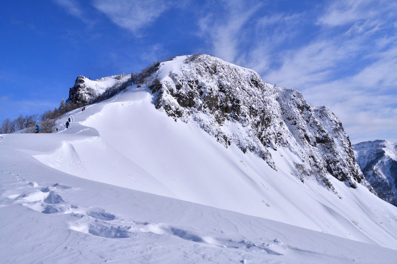 「冬の断崖絶壁に挑む登山者と足跡」の写真