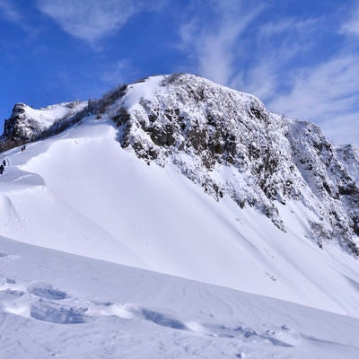 冬の断崖絶壁に挑む登山者と足跡の写真