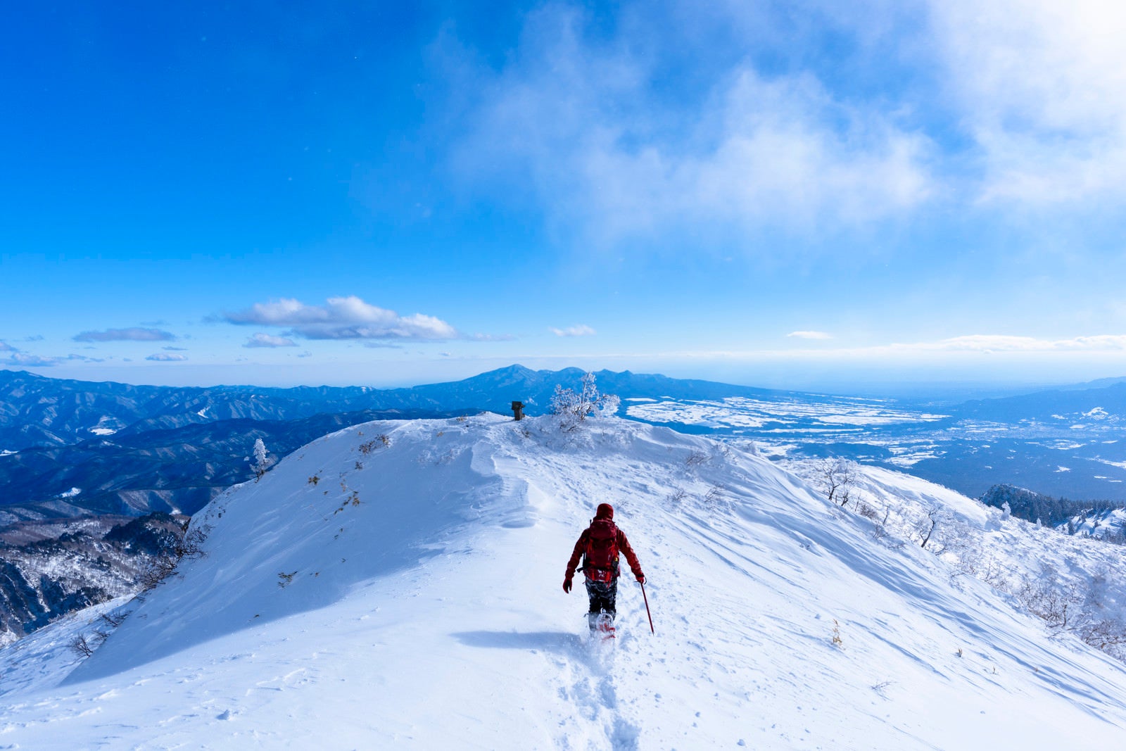 「雪原を走る赤い登山者（上州武尊山）」の写真