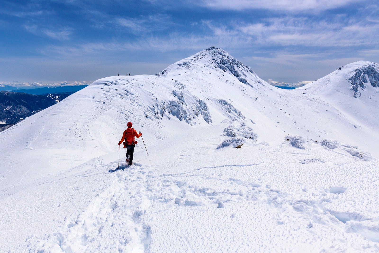 「冬の乗鞍岳を登る赤い登山者」の写真