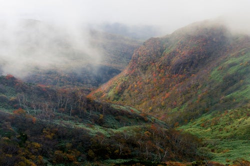 ガスの隙間から紅葉が見える那須岳中腹の写真