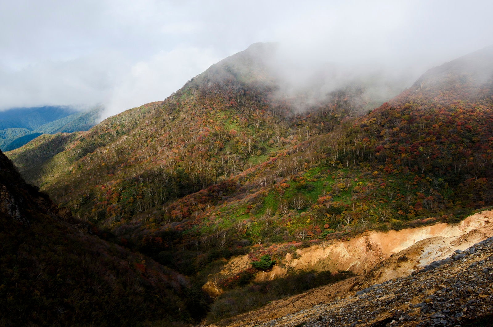 「雲の隙間から紅葉をのぞかせる那須岳（なすだけ）」の写真