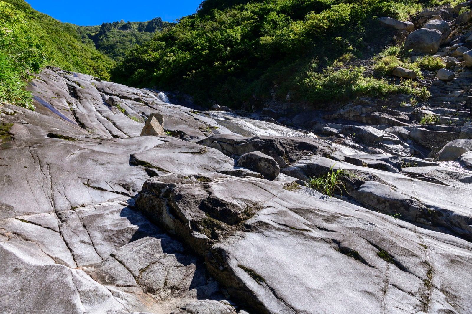 「悠久の水の流れで削られた滑沢の岩（巻機山）」の写真