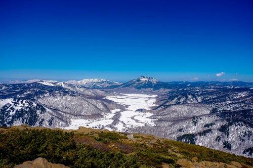 雪が解け始めた至仏山の山肌と燧ヶ岳（ひうちがたけ）の写真