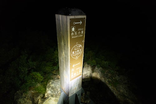 深夜にライトを当てた赤石岳にある指導標（南アルプス）の写真