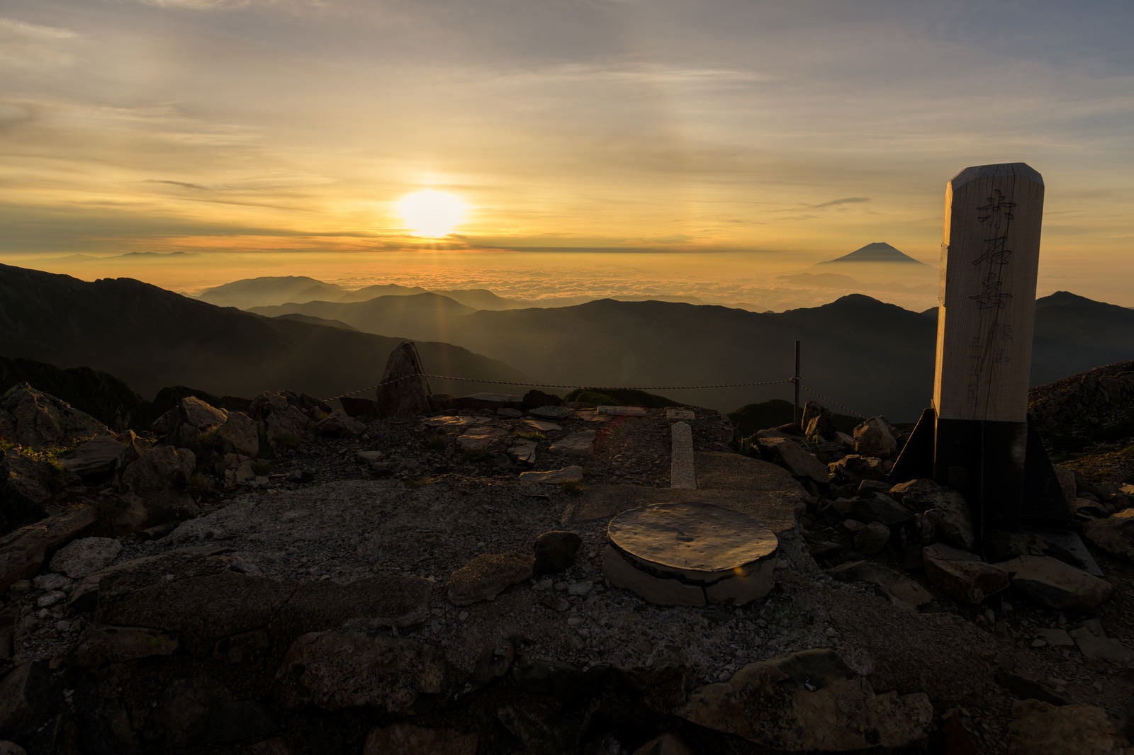 「朝日に照らされる赤石岳山頂碑（南アルプス）」の写真