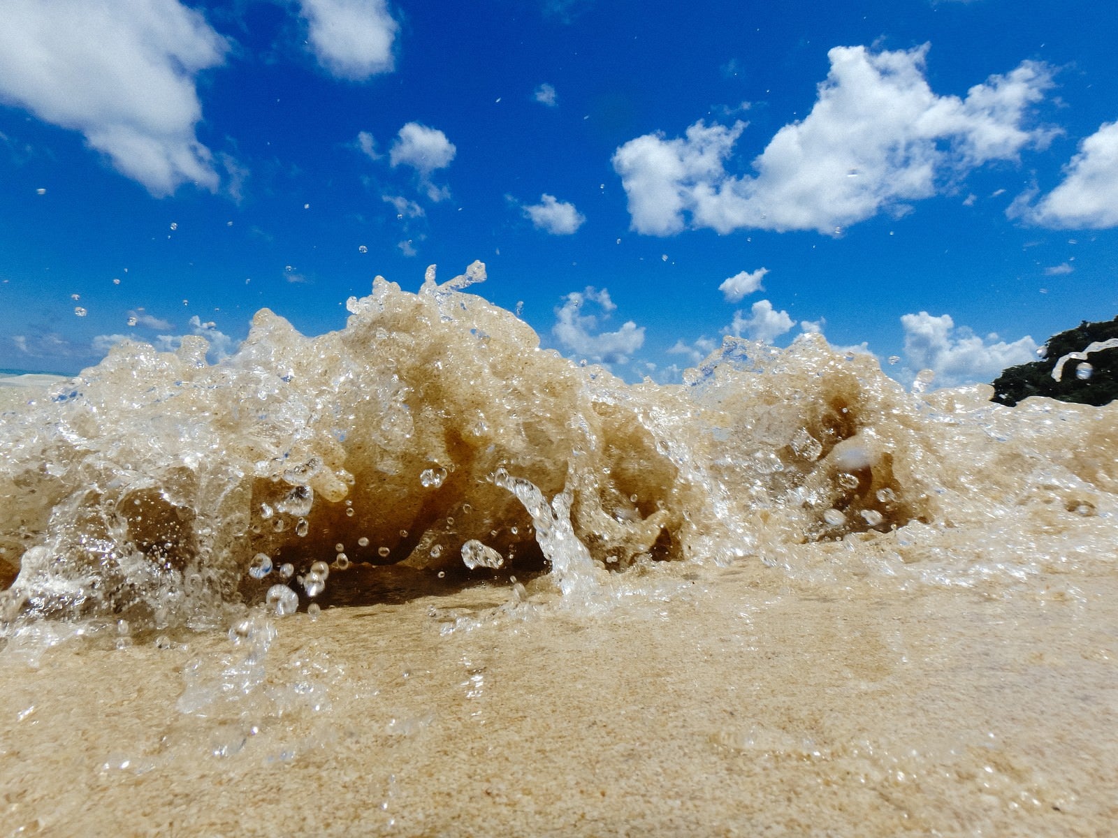 「砂浜に打ち上げるさざ波と水しぶき」の写真