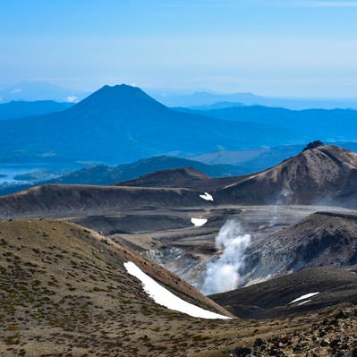 火山から沸き立つ蒸気と雄阿寒岳（北海道釧路市）の写真