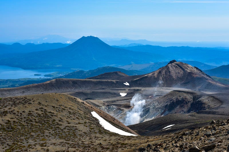 火山から沸き立つ蒸気と雄阿寒岳（北海道釧路市）の写真