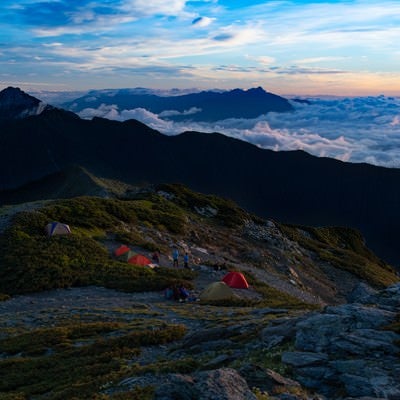 南アルプスの壮大な夜明けを楽しむ登山者の写真