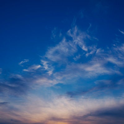 ダイナミックな動きを見せる雲と焼ける地平線の写真