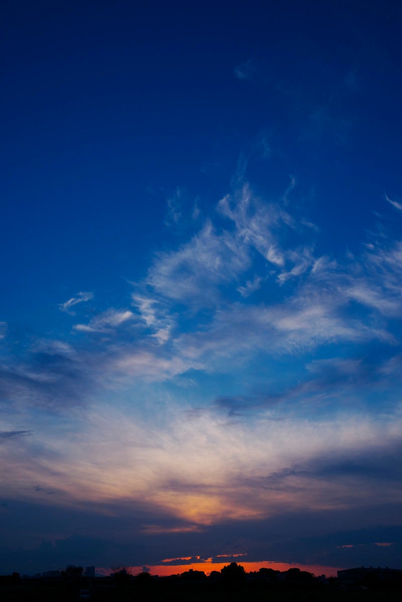 「ダイナミックな動きを見せる雲と焼ける地平線」の写真