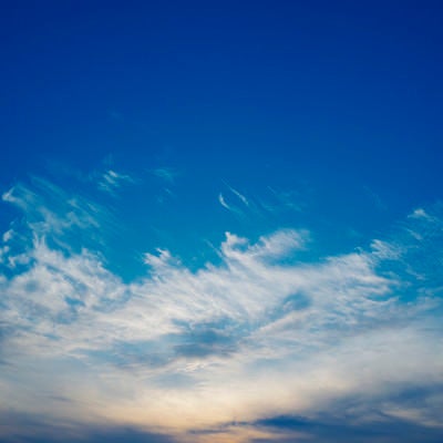 真っ青な空に広がる雲と夕日の写真