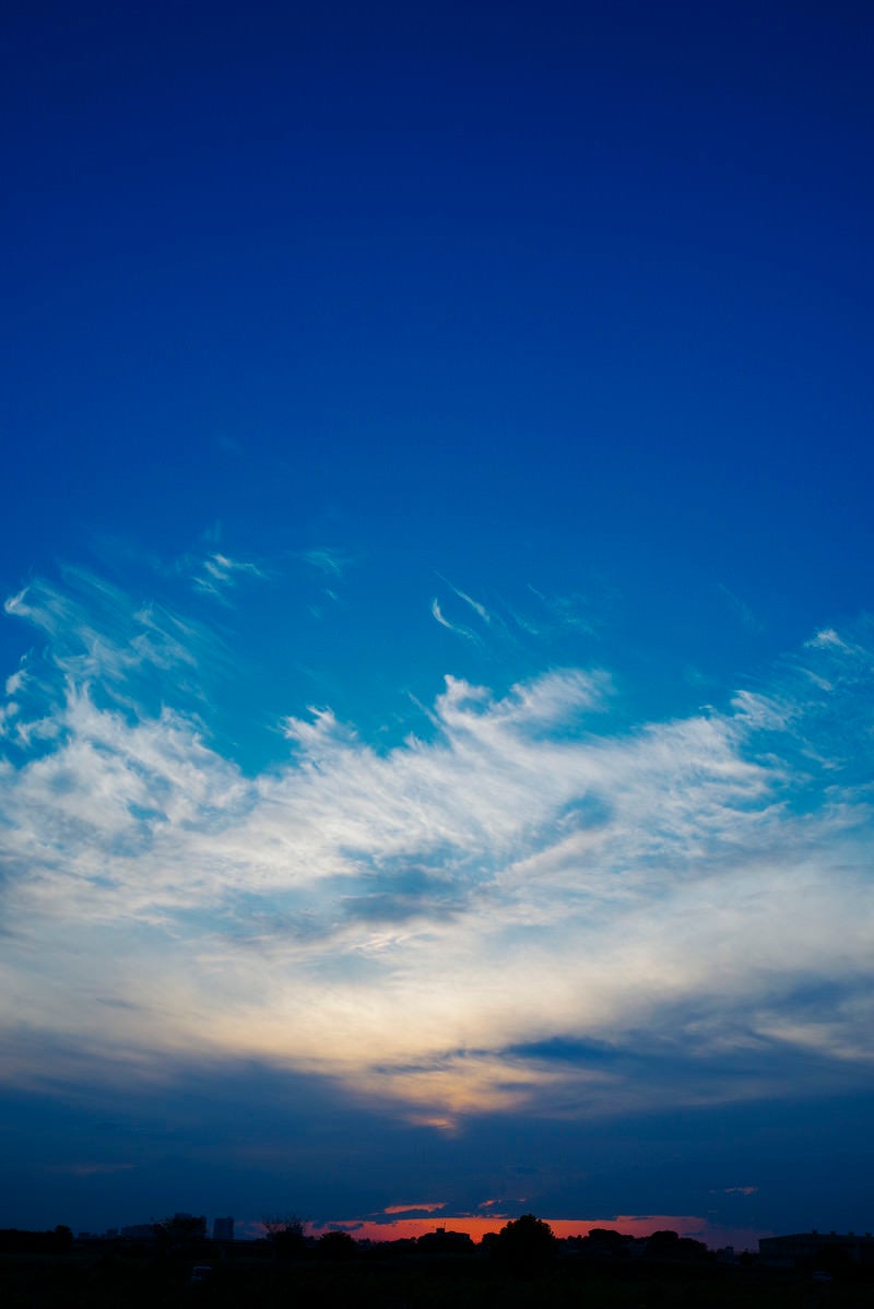 「真っ青な空に広がる雲と夕日」の写真