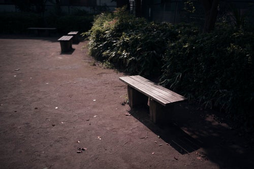 座る人のいない公園のベンチの写真