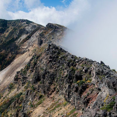 雲が押し寄せる外輪山と稜線の写真