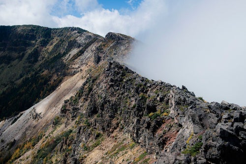 雲が押し寄せる外輪山と稜線の写真