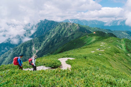 爺ヶ岳から種池に下る登山者と北アルプス北部の山々の写真